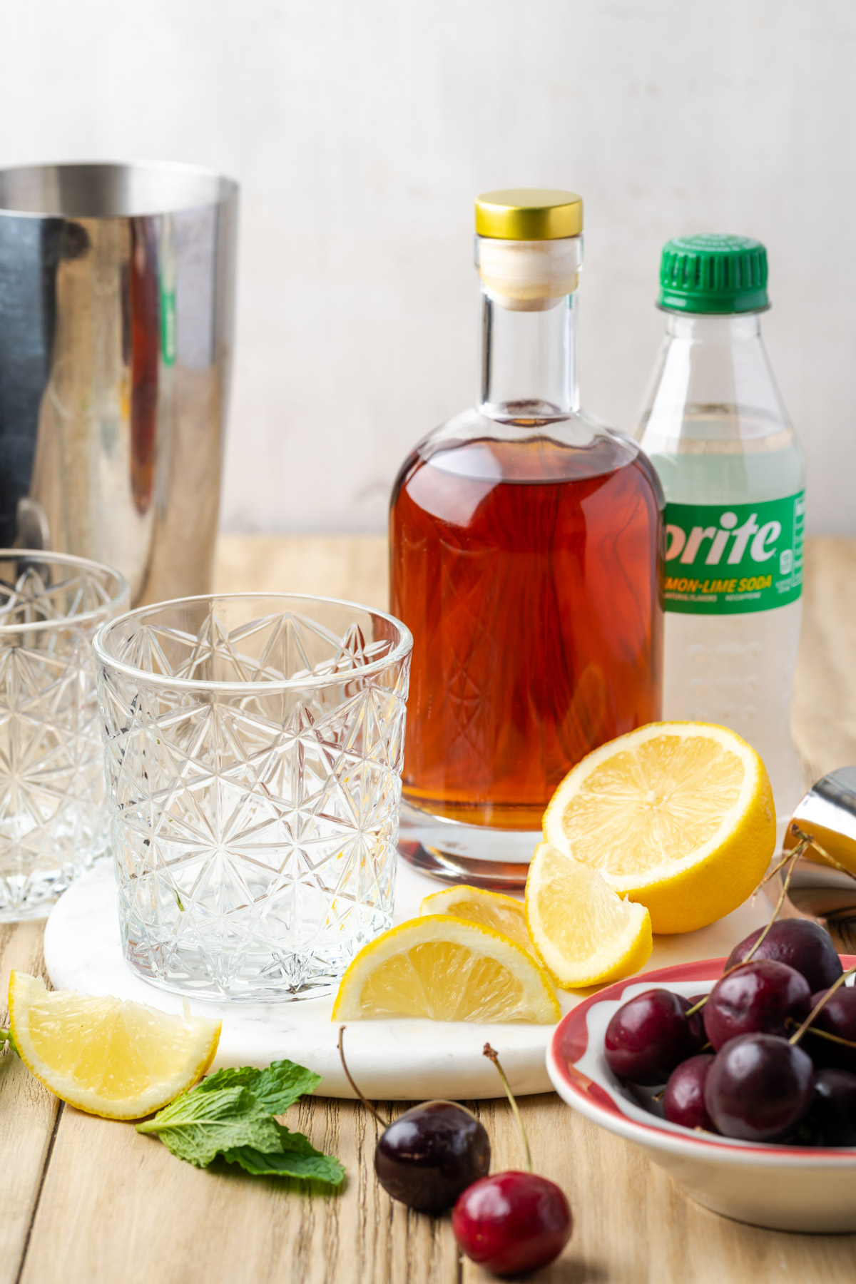 Ingredients for a cherry bourbon smash sitting on a wood table.