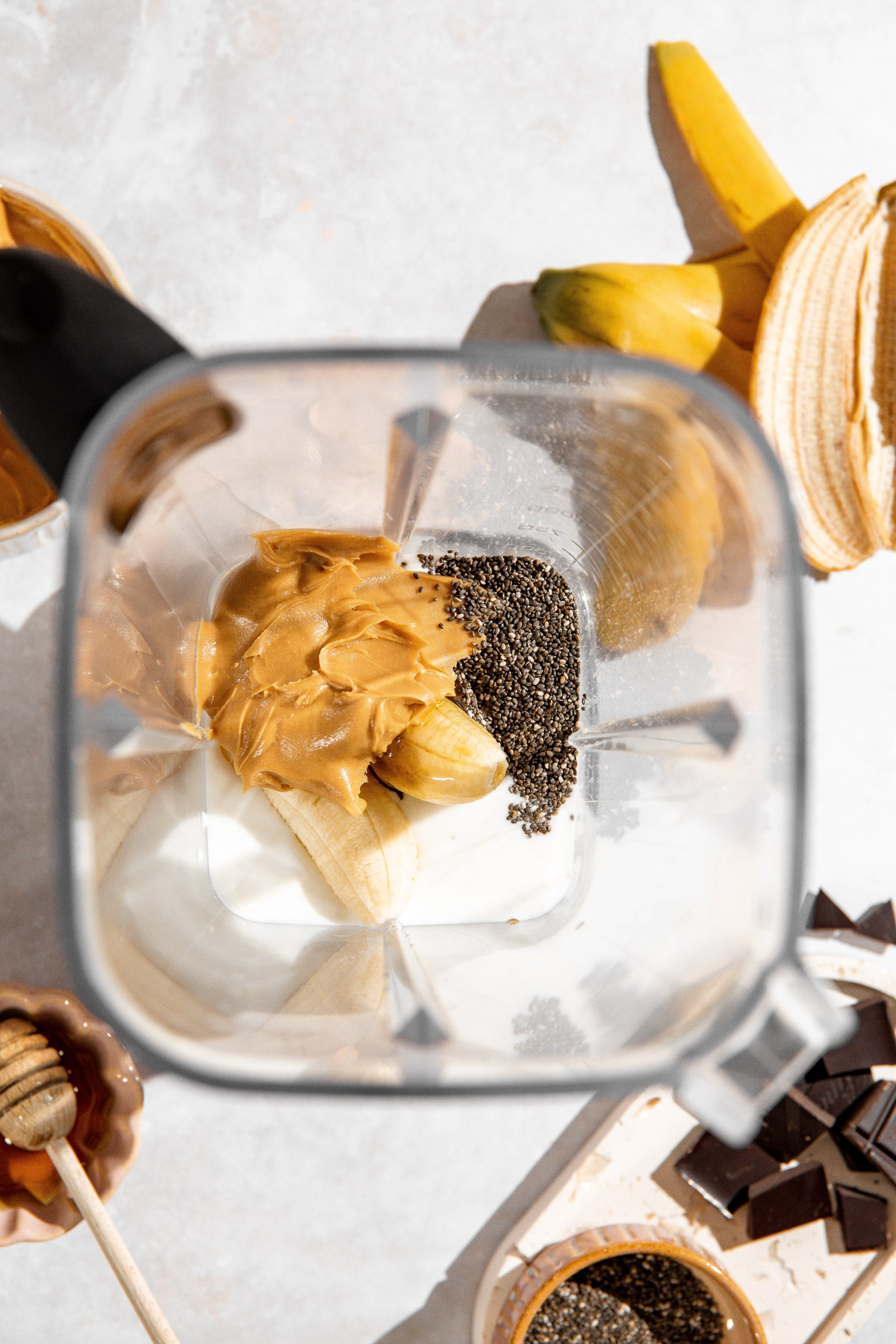 Peanut butter, bananas, chia seeds, honey and milk inside a blender.