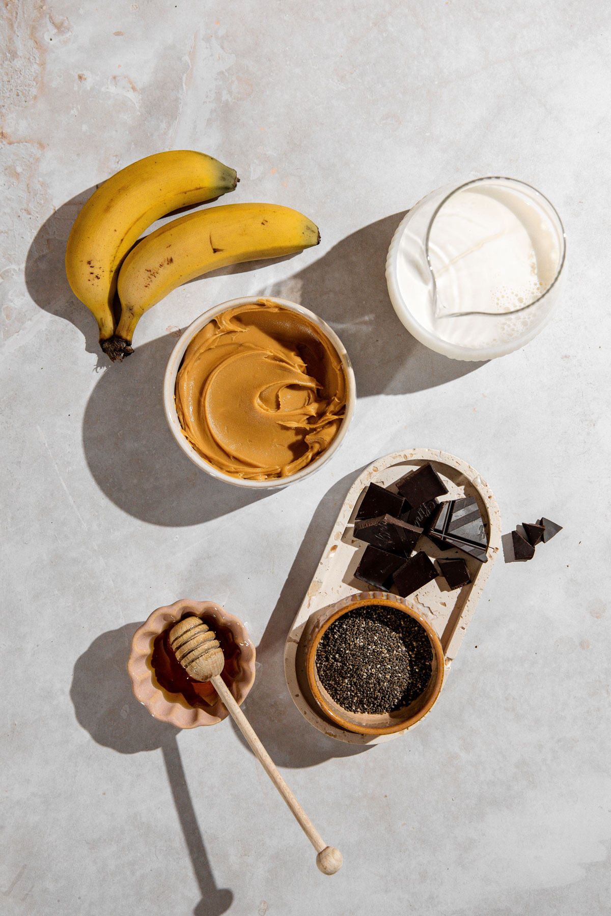 Ingredients for a chocolate peanut butter smoothie sitting on a concrete counter.