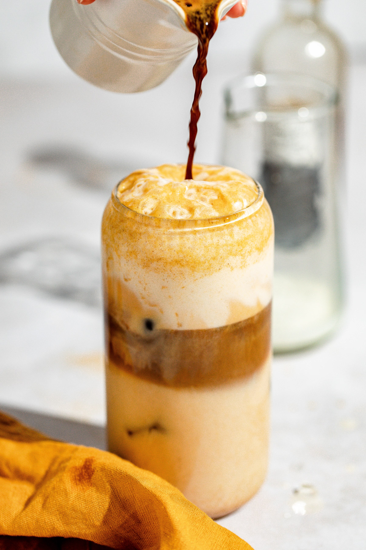 Espresso being poured into the glass with the pumpkin spice milk.