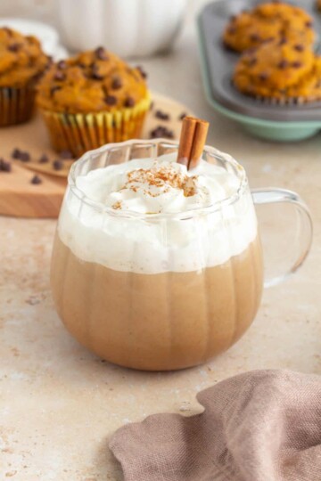 A pumpkin spice latte served in a pumpkin mug topped with whipped cream.