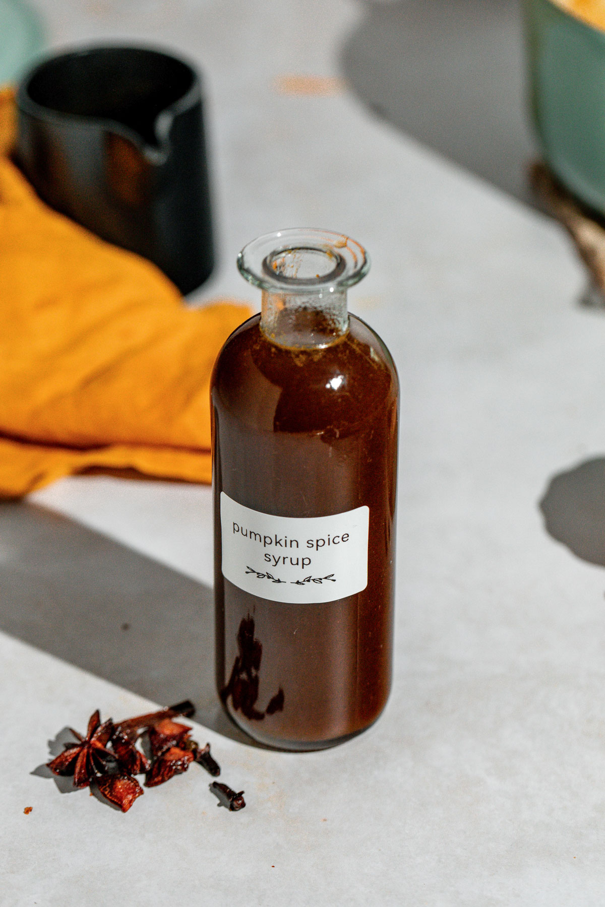 A jar of pumpkin spice syrup sitting on a concrete countertop.