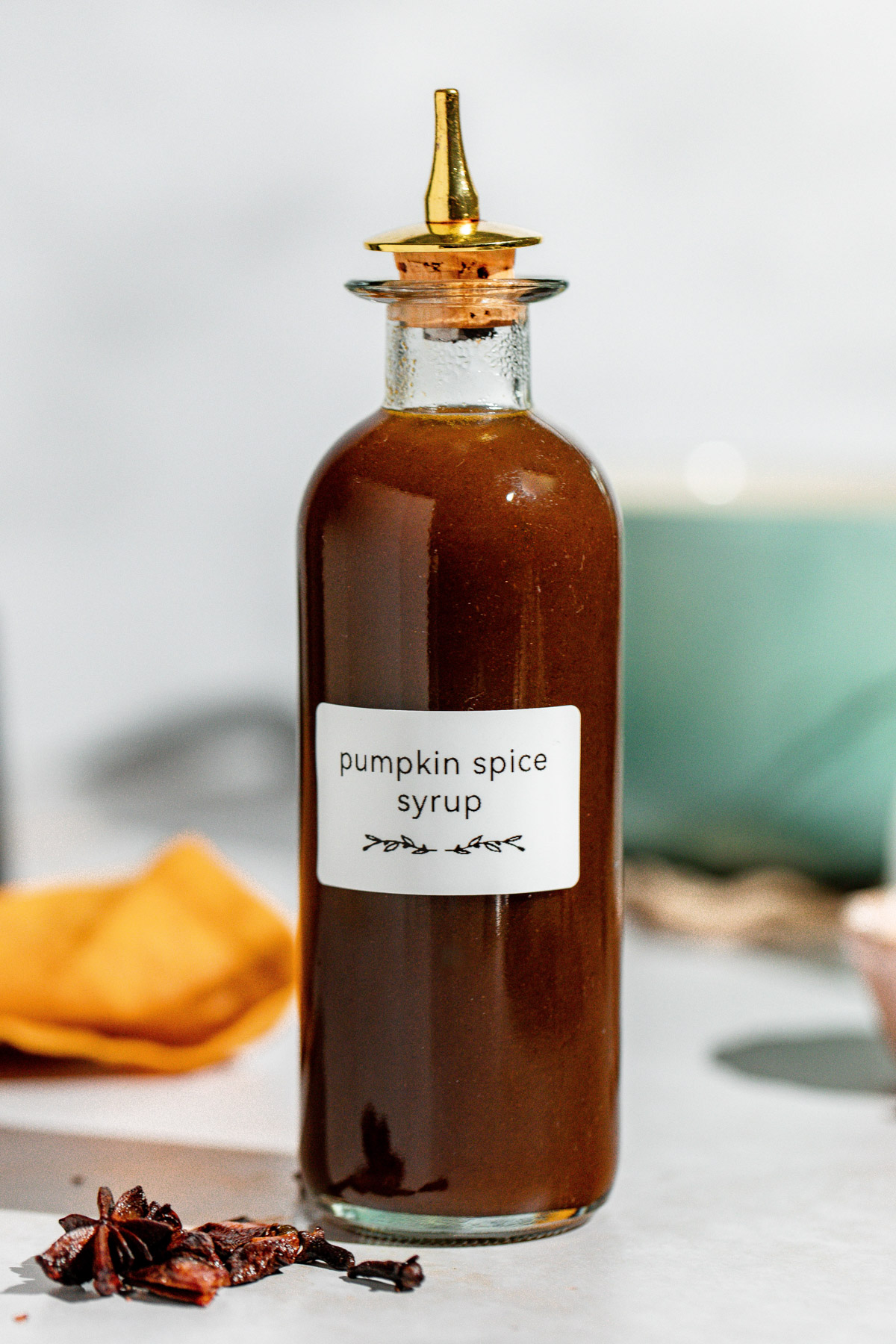 A small jar containing pumpkin spice syrup sitting on a white counter.