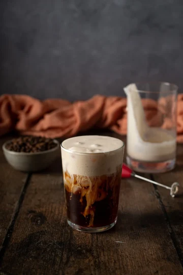 A glass of coffee topped with pumpkin cold foam.