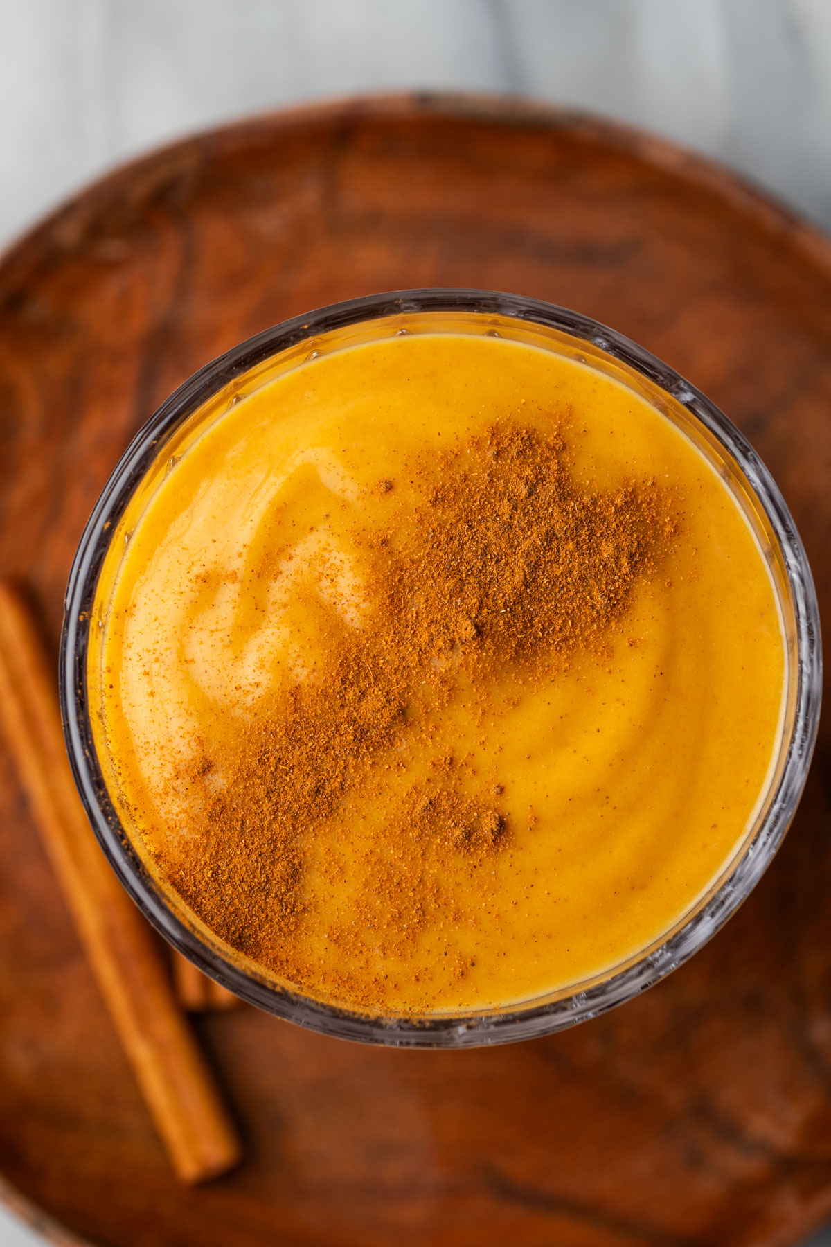 The top of a glass of pumpkin spice smoothie garnished with a sprinkle of cinnamon.