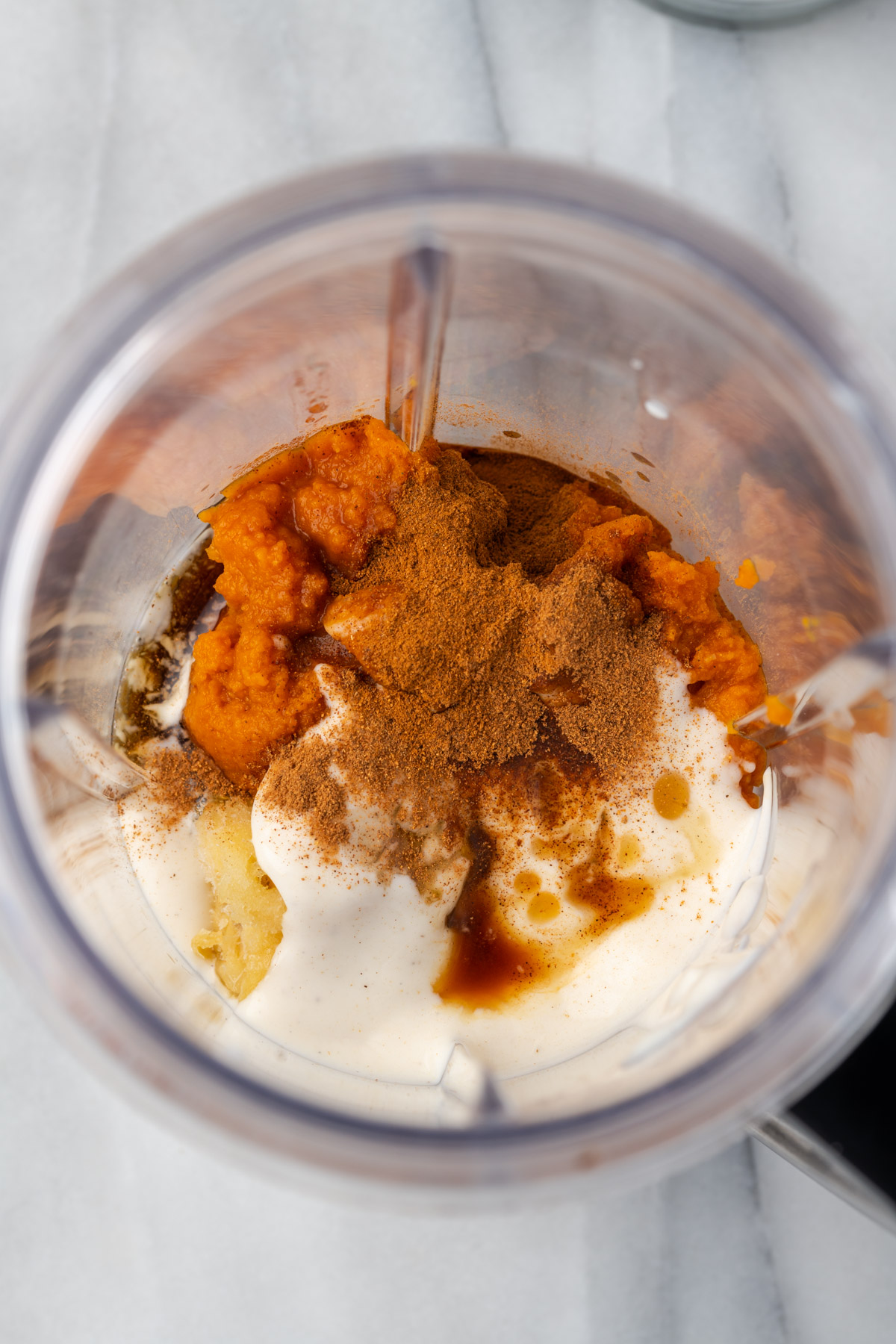 Ingredients for a pumpkin spice smoothie inside of a blender.