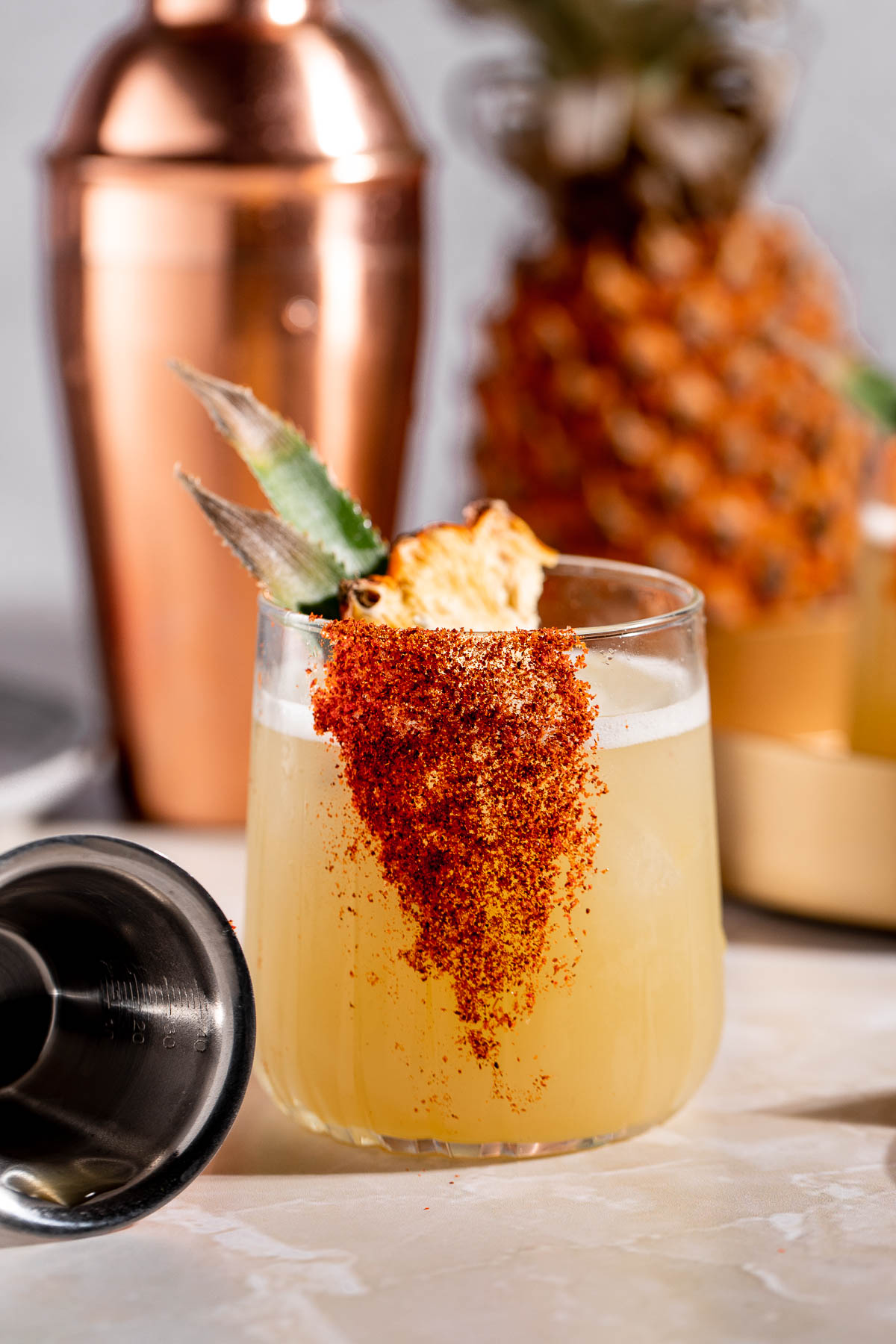 A mezcalita served with a slice of dried pineapple sitting on a marble countertop.