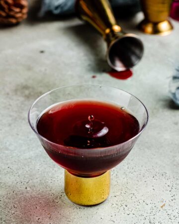 A moody black heart cocktail in a festive coupe glass sitting on a counter.