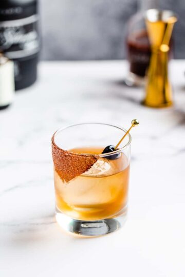 A mezcal chocolate cherry cocktail sitting on a marble counter.