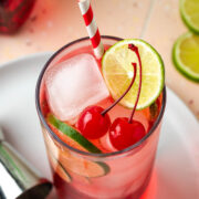 A dirty shirley cocktail garnished with lime slices and cherries.