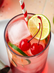 A dirty shirley cocktail garnished with lime slices and cherries.