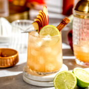 An apple cider margarita garnished with fresh apple slices and a lime wedge.